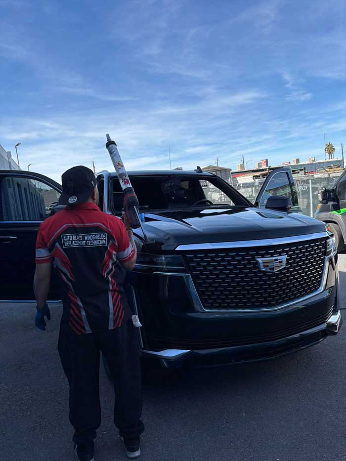 Technician working at the windshield of a black Cadillac Escalade in Las Vegas