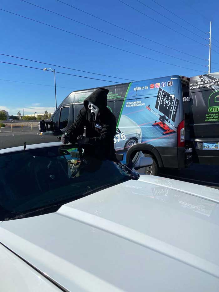 Halloween-costumed technician removing a vehicle windshield