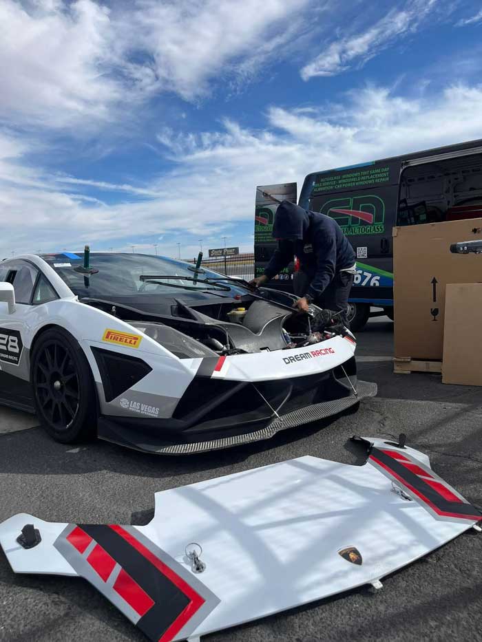 Technician preparing the exposed windshield cowl of a Lamborghini with its hood removed